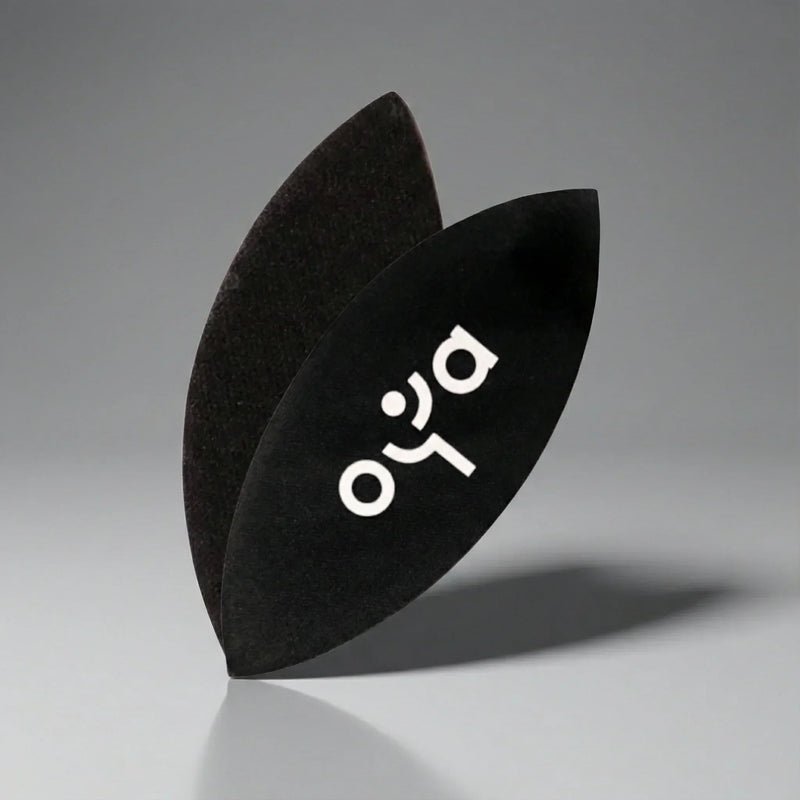 Two black oval-shaped Oya Femtech apparel patches with white logo on gray background
