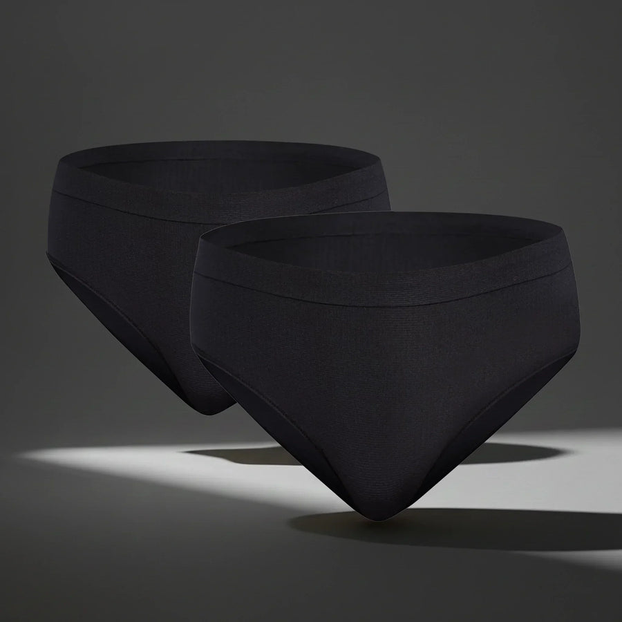 Two black seamless women's underwear briefs floating on gray background