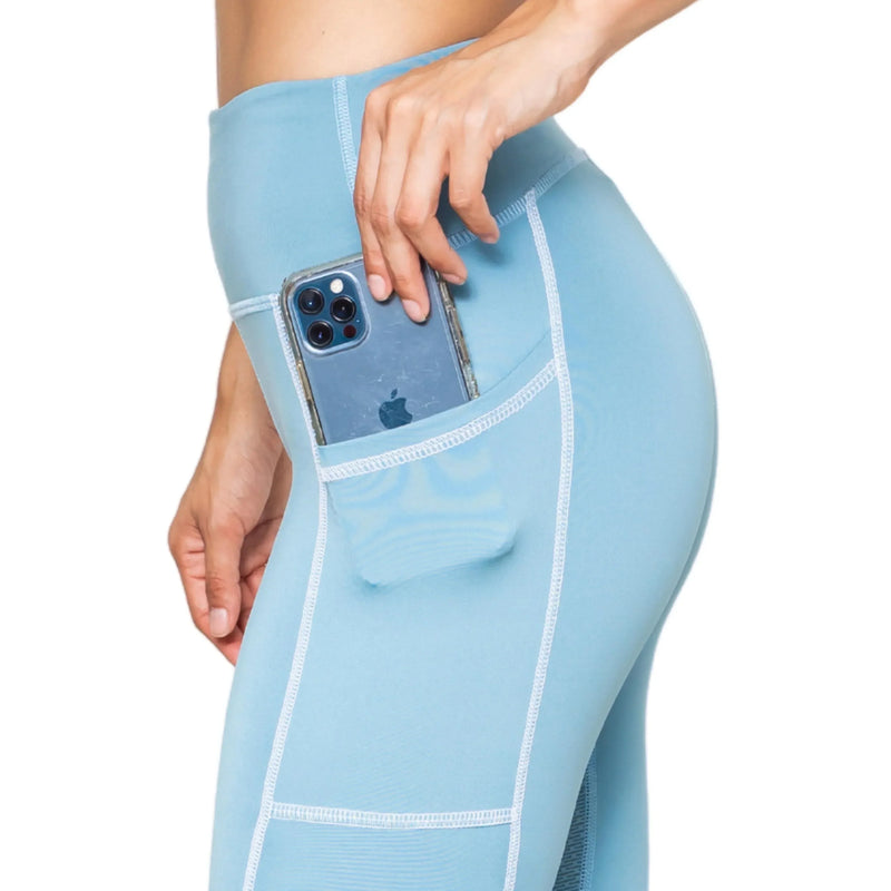 Close-up of woman wearing light blue femtech leggings with side pocket holding a smartphone