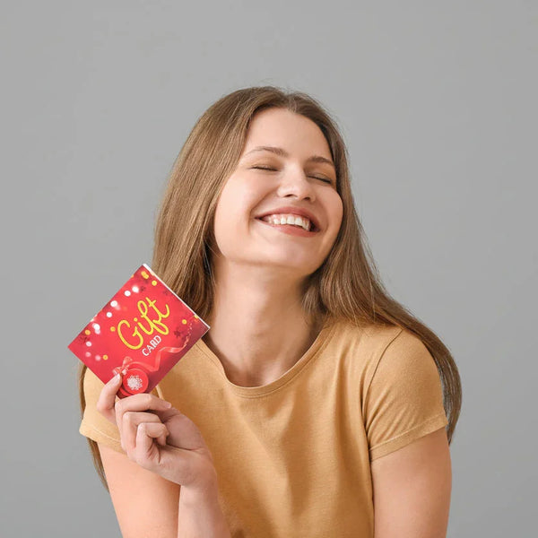 Smiling woman in beige shirt holding a red gift card with yellow text on gray background